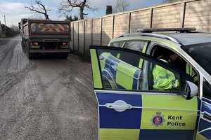 Police are parked behind a large lorry carrying waste