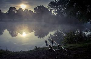 Two fishing rods set up beside a river at dawn