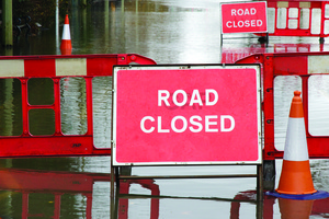 Photo of a road closed sign with standing water in background