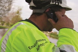 Man in Environment Agency branded jacket on the mobile telephone