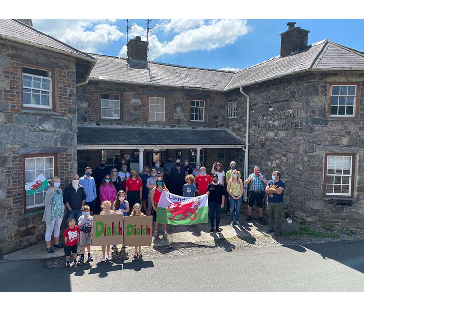 Members of the community and local volunteers gathered outside the Ty’n Llan pub entrance with banners and signs