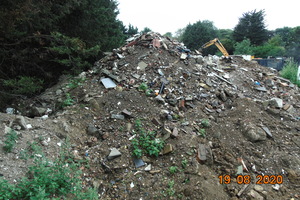A photograph of a large pile of earth with waste mixed in it.