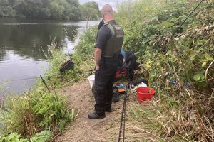 An Environment Agency officer speaks to an angler by the river