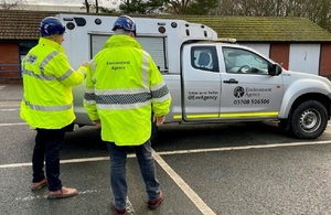 Environment Agency officers stood next to an EA vehicle.