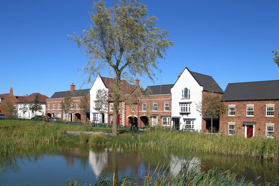 Photo of housing with a large pond in the foreground.