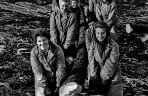 Black and white image of women lifting a heavy tree trunk