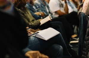 Blurred image of people sitting down at a conference.