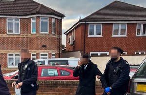 Officers arresting an individual, faces are obscured.