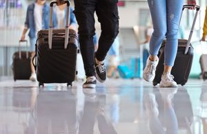 Back view of people pulling suitcases through a travel terminal.