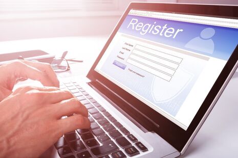 an imagine of a person's hands over a keyboard – the person is filling in a registration form