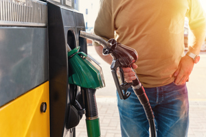 Мужчина на заправочной станции заправляет бак своей машины дизельным топливом