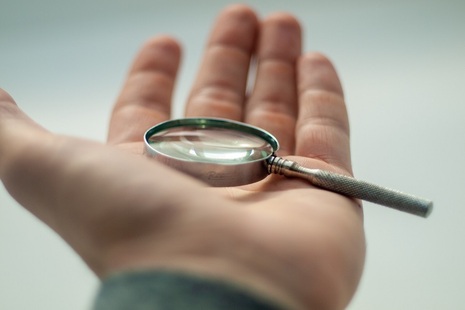 hand holding a small magnifying glass