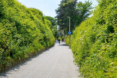 View of someone cycling down a pedestrian and bicycle path between grassy embankments