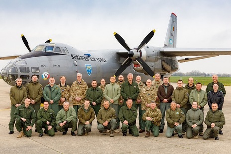 Military personnel posing in front of an airplane