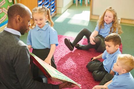 Male teacher reading to a small group of pupils