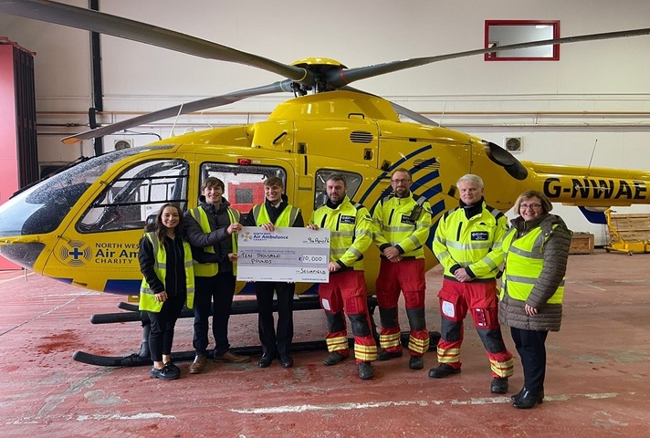 Trainees and Pauline Deans from our social impact team present a cheque to members of the North West Air Ambulance crew.