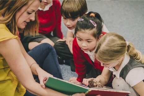 teacher with primary school children reading a book