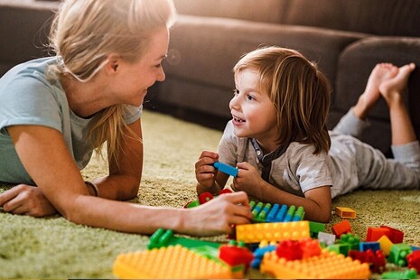chilminder and child playing with building blocks