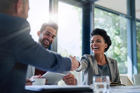 Business people shaking hands and smiling - Shutterstock