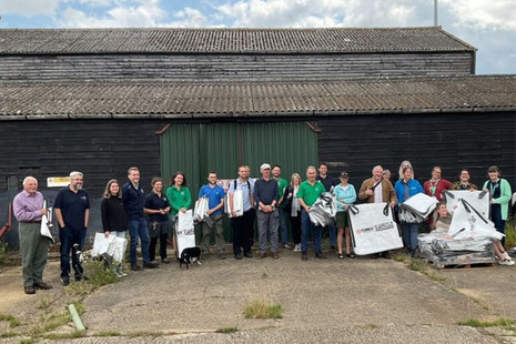 A group of people (Forest Plastics Working Group) stand outside a recycling hub. They are holding bags ready to collect plastics.