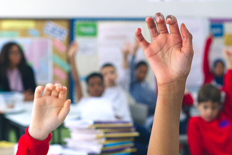 classroom of children with their hands in the air
