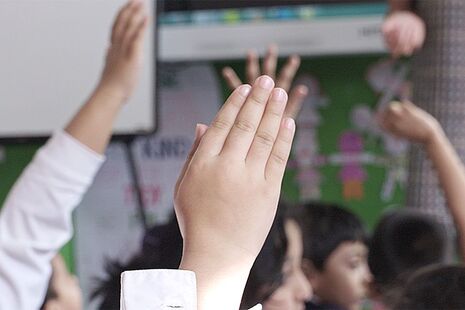 Children with hands raised in a classroom