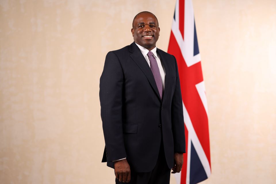 Foreign Secretary  David Lammy standing next to the flag