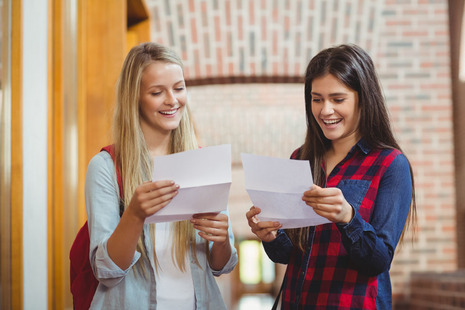 Two female students looking happy as they look at their exam results