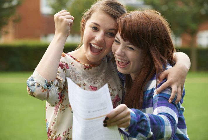 Two female students looking happy as they look at their exam results