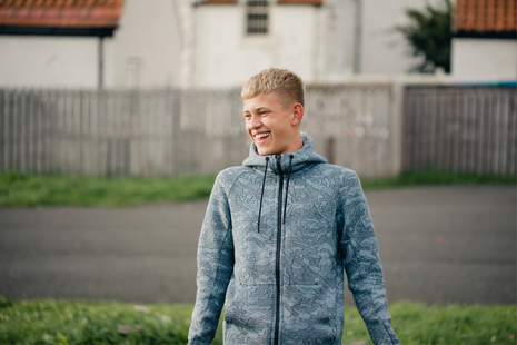 A boy in a grey hoodie smiling.