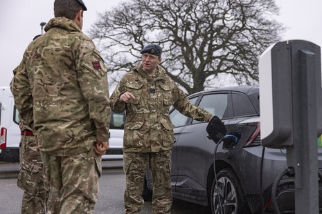 An electric vehicle being charged by some people in military uniform