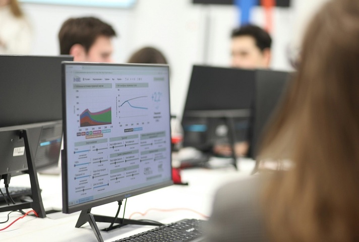 Colourful graphs on a computer screen with a woman's blurred head.