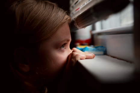 Young girl peeping out of window