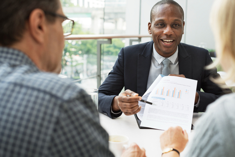 A male employee shows colleagues a report. 