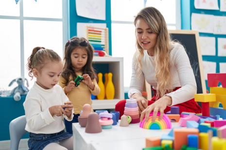 Childcare provider with 2 children playing with toys