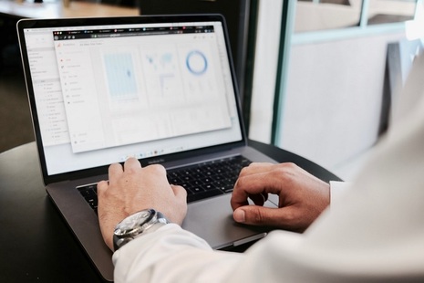 Man at laptop, on which is displayed several charts. Credit: Unsplash