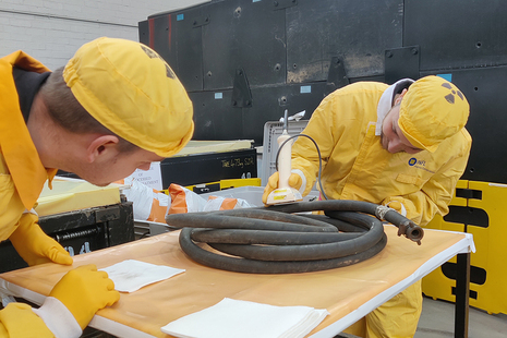 Joshua Bettles wearing PPE carries out a monitoring task under a team member's supervision