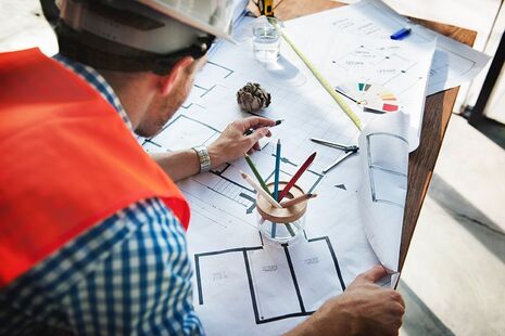 person wearing a hard hat and looking at construction plans