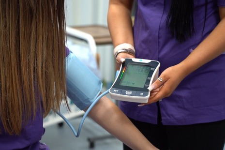 promoting health care courses - picture of a health practitioner taking a patient's blood pressure