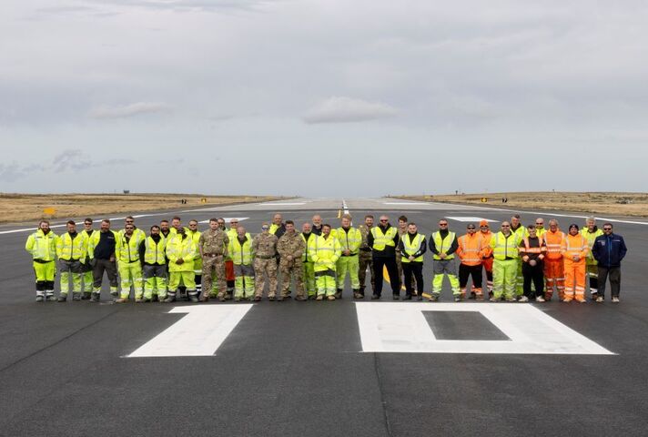 A group of people in high-vis jackets on a runway 