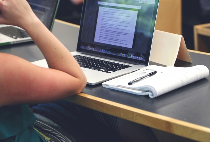 A female student using a laptop with a notepad beside it