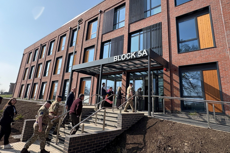 A group of people walking up steps to enter a large three storey building with the words 'Block 5A' on a sign above the entrance.