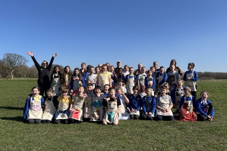 Photograph of the group of school children sitting outside on grass under a blue sky