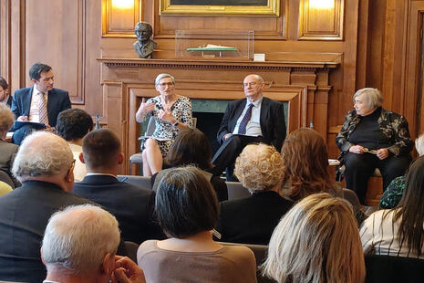 A photograph of Dame Clare Moriarty, Dr Bill Kirkup, Doug Chalmers and Gillian Peele engaged in a panel discussion in front of an audience.