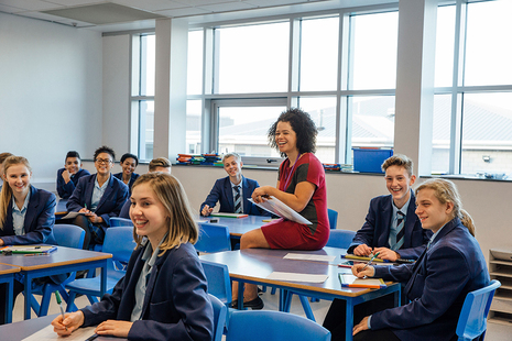 teacher amongst classroom of happy pupils