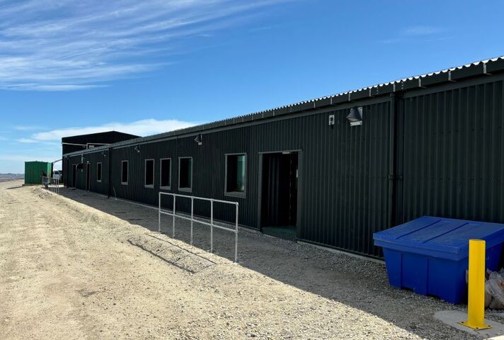 The exterior of a single story accommodation block sits in front of a bright blue sky in the Falkland Islands