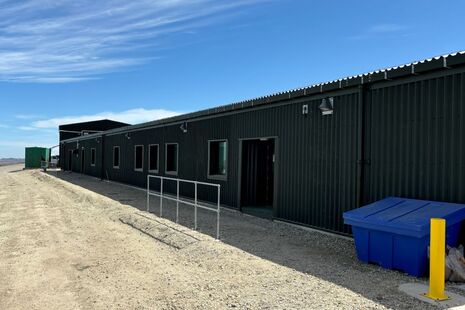 The exterior of a single story accommodation block sits in front of a bright blue sky in the Falkland Islands