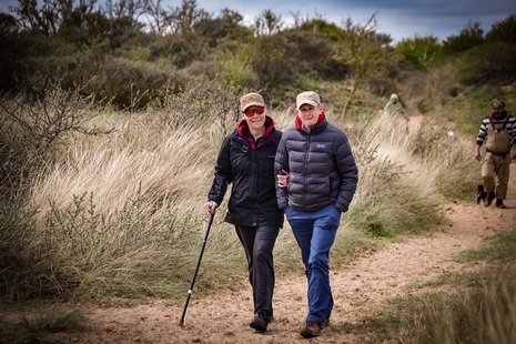 Photograph of a man and a woman walking along a track surrounded by green vegetation.