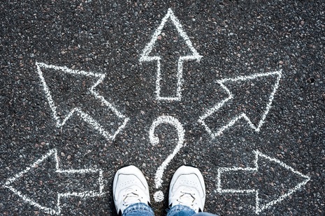 Arrows and a question mark drawn in white chalk on a black road.