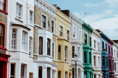 A row of victorian terraces with bay windows, with each house painted in a different, vibrant colour.